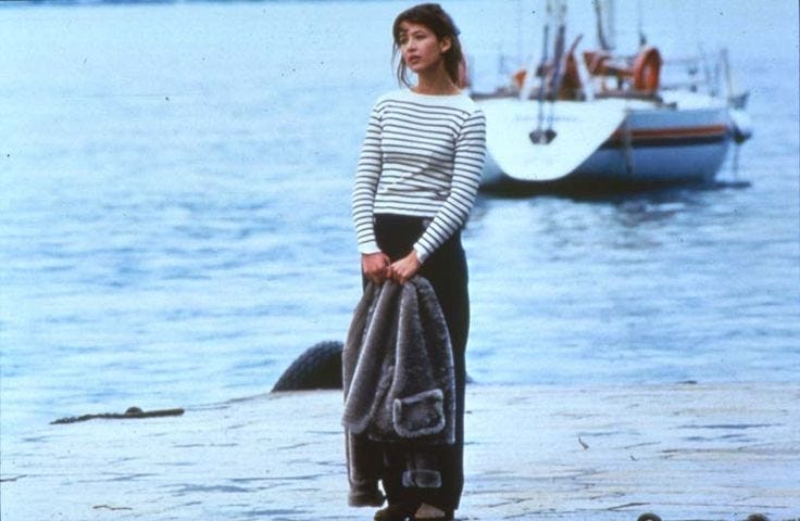 This may contain: a woman standing on the beach with a towel wrapped around her