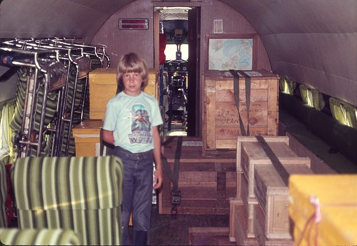 Boy (author) standing inside airplane with boxes lining one side.