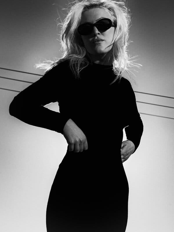 Olivia Nuzzi wears sunglasses and a black turtleneck. Her blond hair flies around in the wind. Olivia Nuzzi wears sunglasses and a black turtleneck. Her blond hair flies around in the wind.