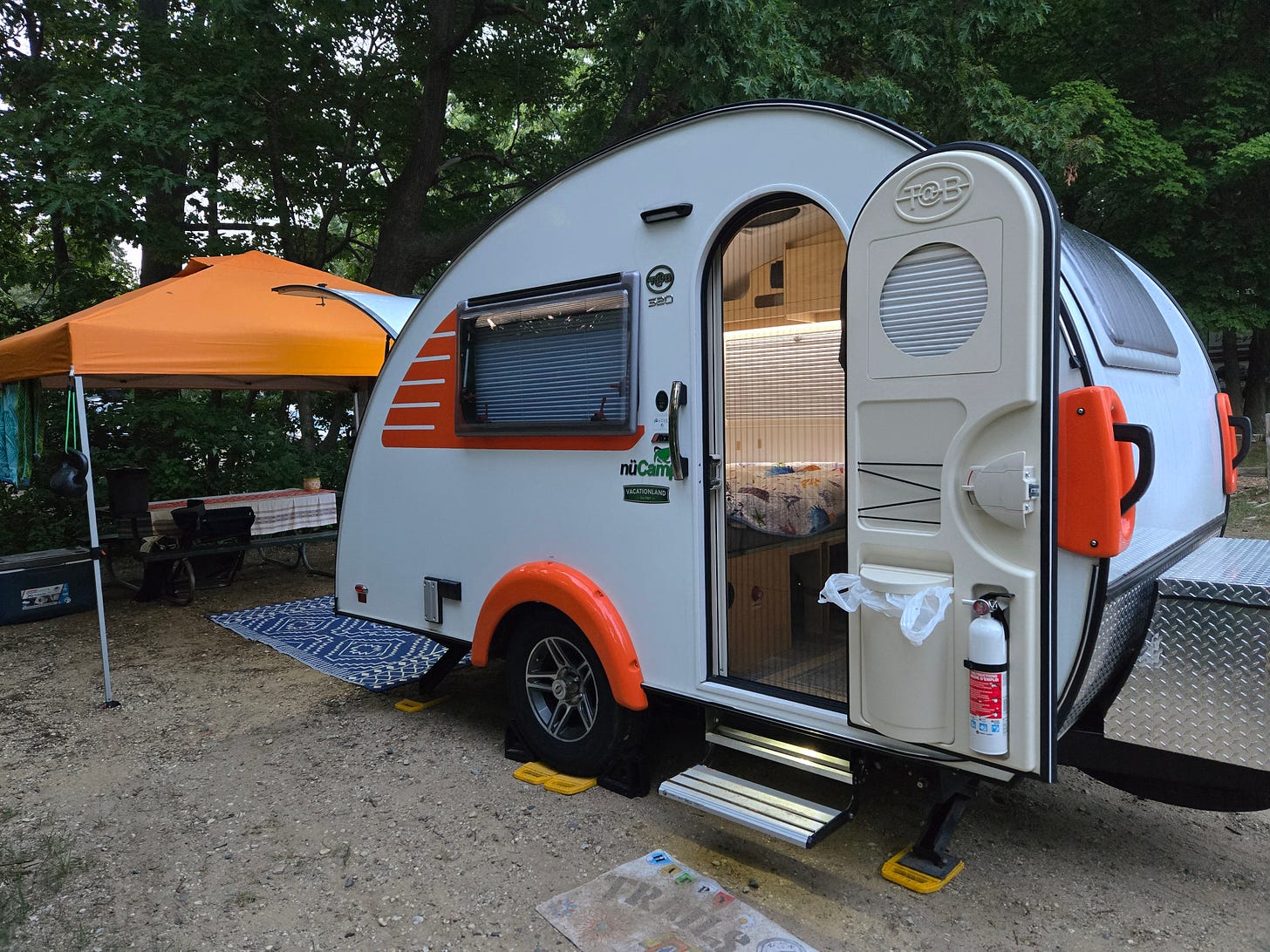 teardrop camper with a canopy off the back to create a protected sitting and dining area.