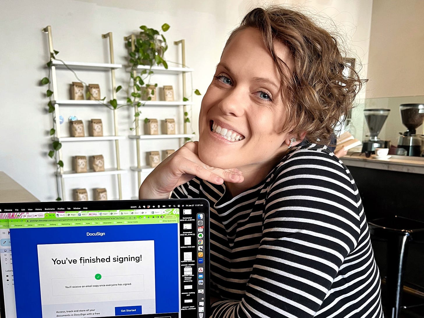 Caroline Davis smiling at her desk in a black and white striped sweater beside a laptop showing a DocuSign literary agent signing confirmation Caroline Davis smiling at her desk in a black and white striped sweater beside a laptop showing a DocuSign literary agent signing confirmation