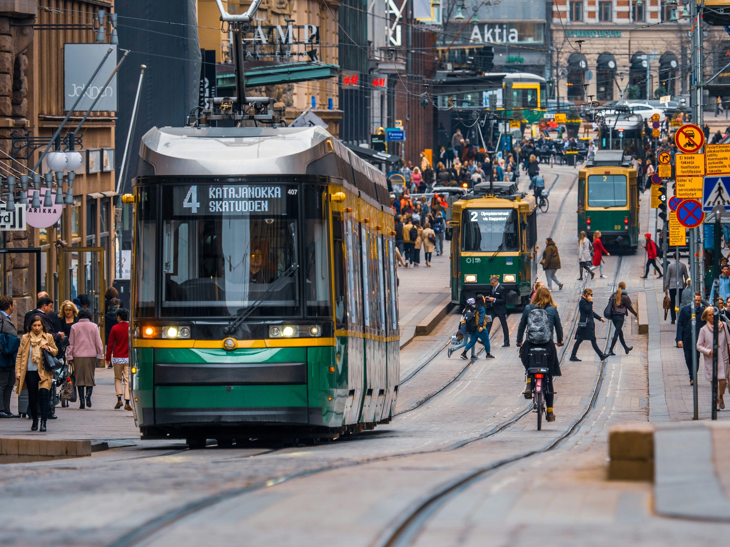Green and yellow city trams in a crowded street in Helsinki, Finland