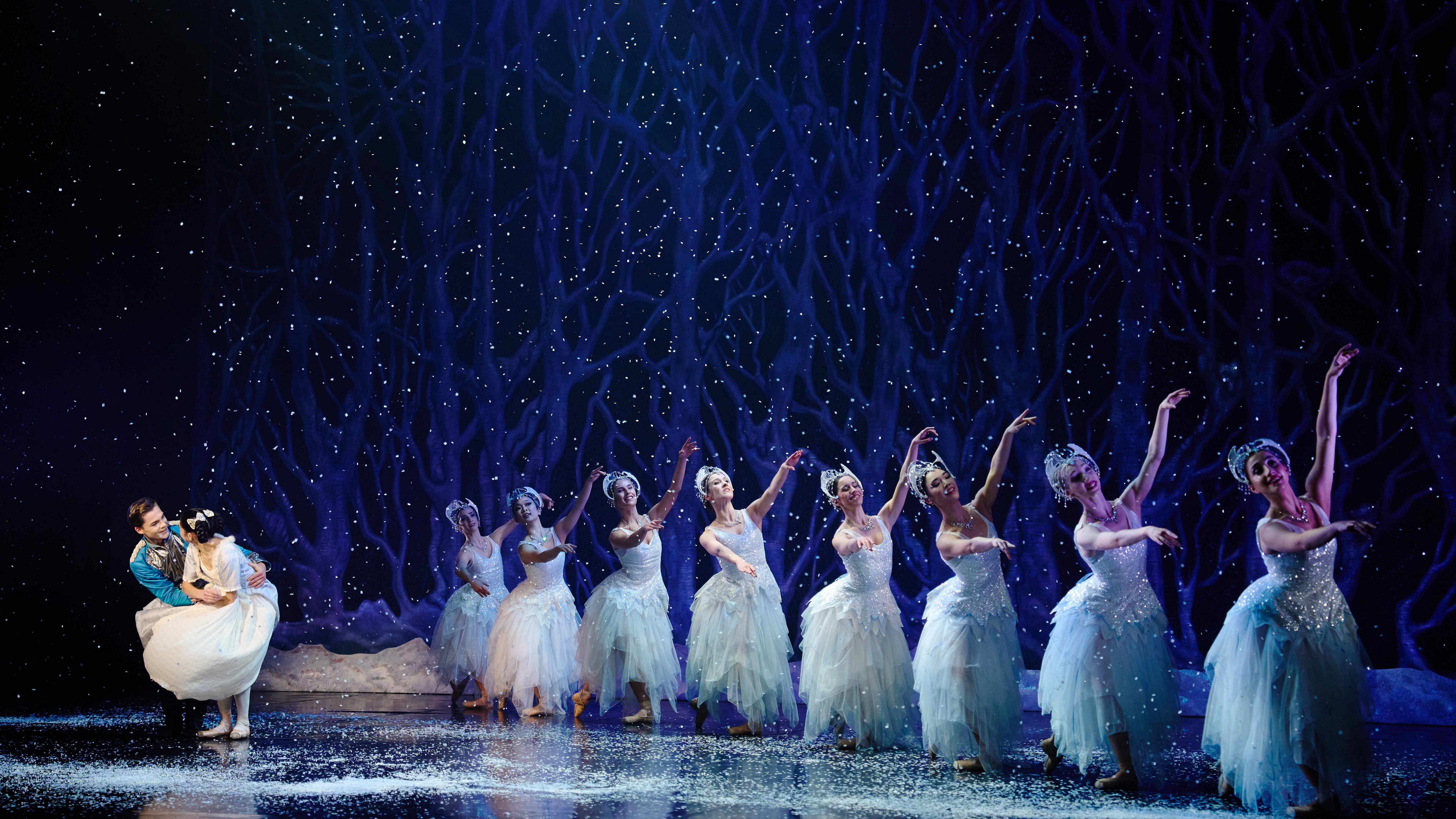 The Prince in his smart blue uniform and Clara in a white dress gaze into each other's eyes as snowflakes dance.