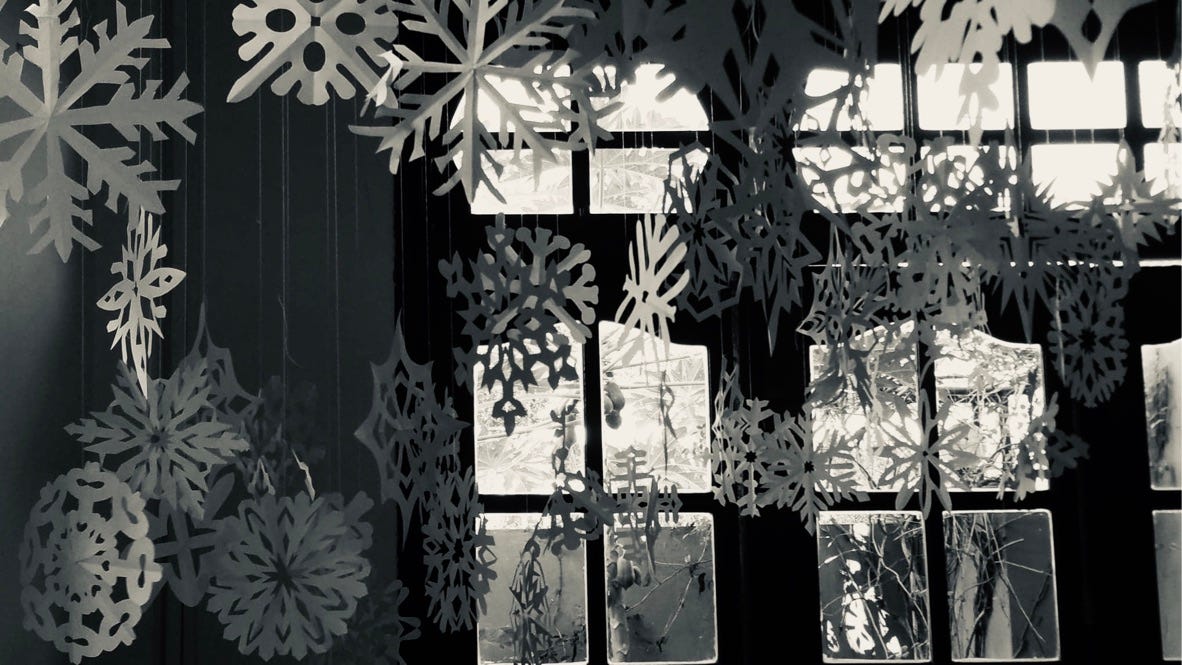 paper snowflakes hanging inside a home with glass window panes in the background. paper snowflakes hanging inside a home with glass window panes in the background.