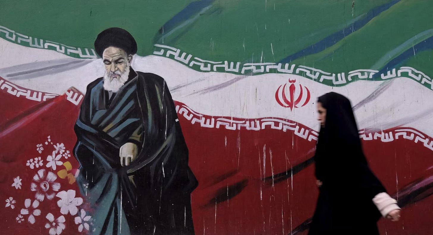 A woman walks past a painting of Iran's late leader Ayatollah Ruhollah Khomeini in Tehran December 11, 2015
