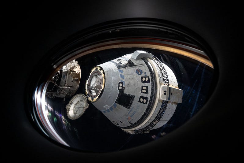a space capsule seen in space through the window of a space station