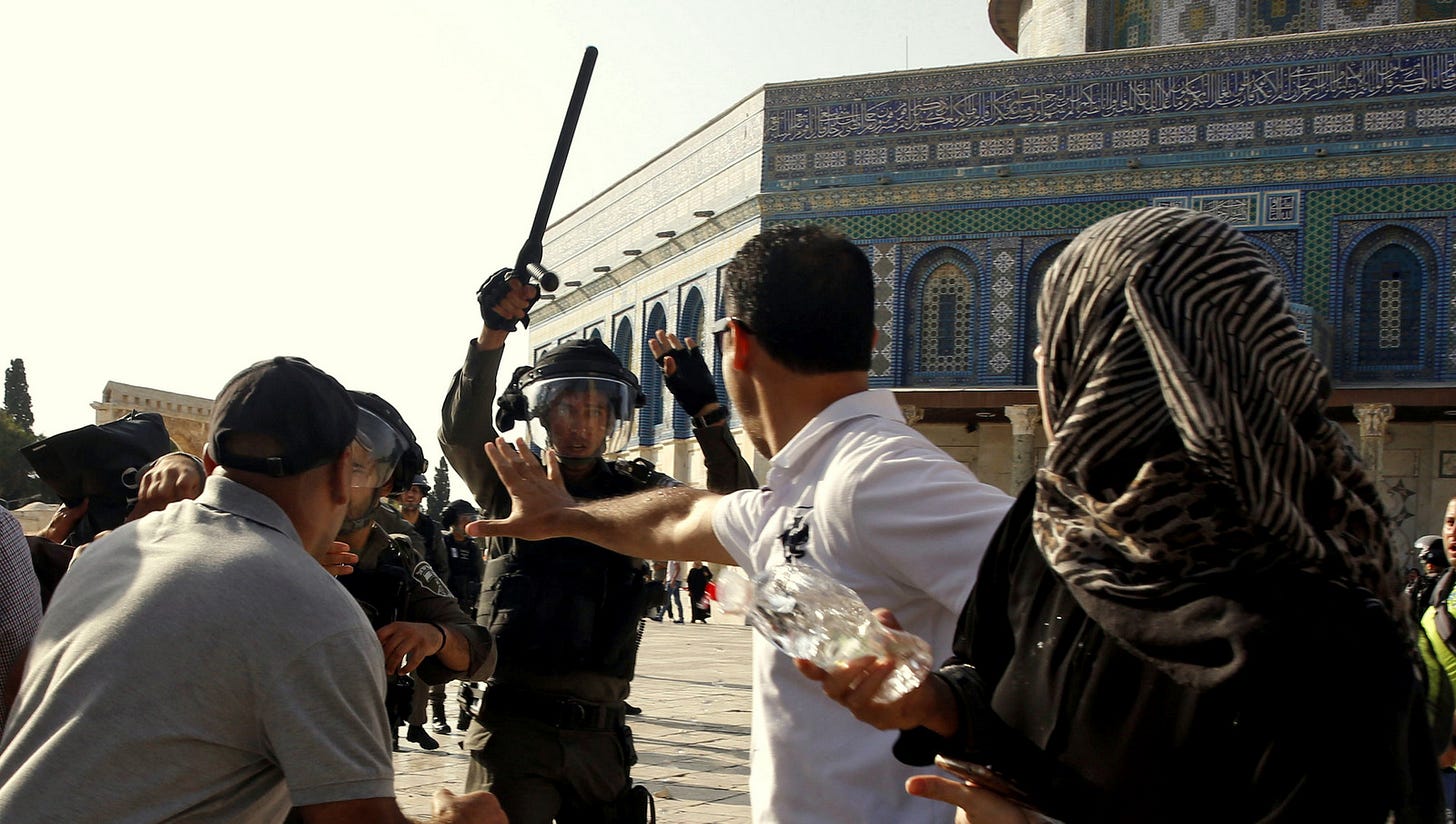 An Israeli police officer raises his baton on Palestinians worshipers near the Al Aqsa Mosque in Jerusalem's Old City, July 27, 2017 (AP/Mahmoud Illean) An Israeli police officer raises his baton on Palestinians worshipers near the Al Aqsa Mosque in Jerusalem's Old City, July 27, 2017 (AP/Mahmoud Illean)