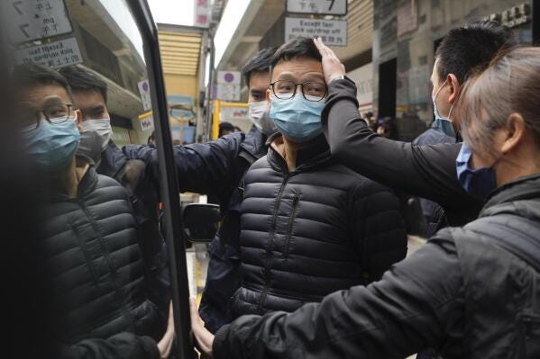 Editor of Stand News Patrick Lam, center, is escorted by police officers into a van after they searched evidence at his office in Hong Kong, Wednesday, Dec. 29, 2021. Hong Kong police raided the office of the online news outlet on Wednesday after arresting several people for conspiracy to publish a seditious publication. (AP Photo/Vincent Yu)