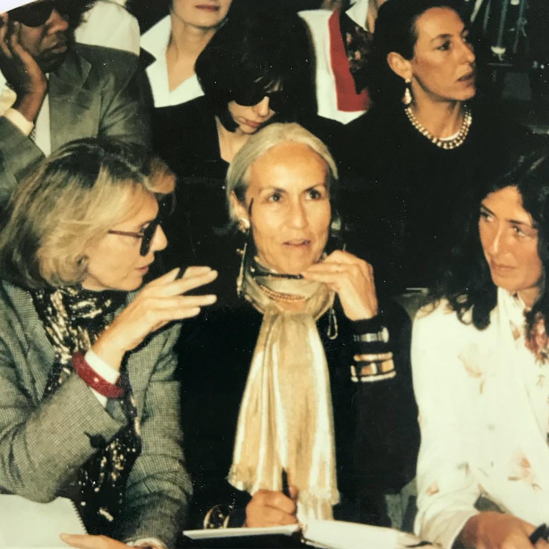 Formally dressed fashion editors sit while viewing a fashion show.