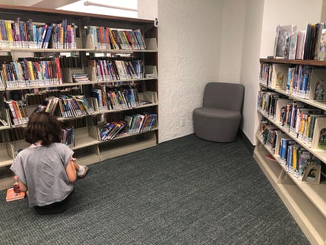 People in library borrowing books, browsing, reading 