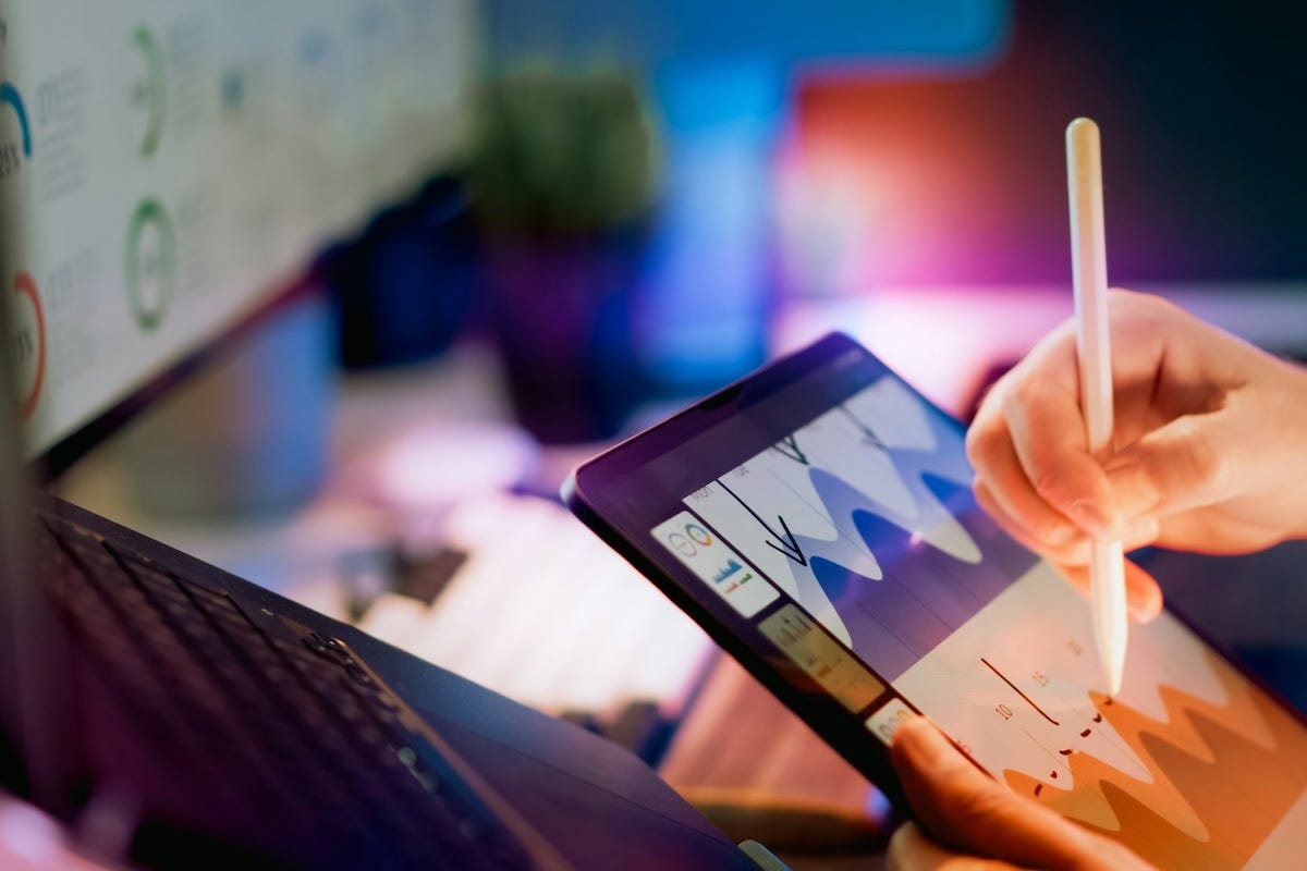 A marketing strategist using a stylus on a tablet to analyze colorful performance charts and growth data. A marketing strategist using a stylus on a tablet to analyze colorful performance charts and growth data.