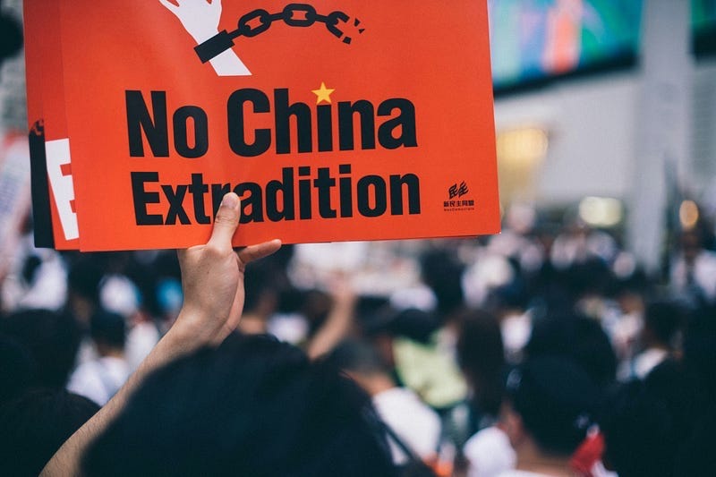 A street protester in Hong Kong holds up a sign that reads, “No China Extradition.” A street protester in Hong Kong holds up a sign that reads, “No China Extradition.”