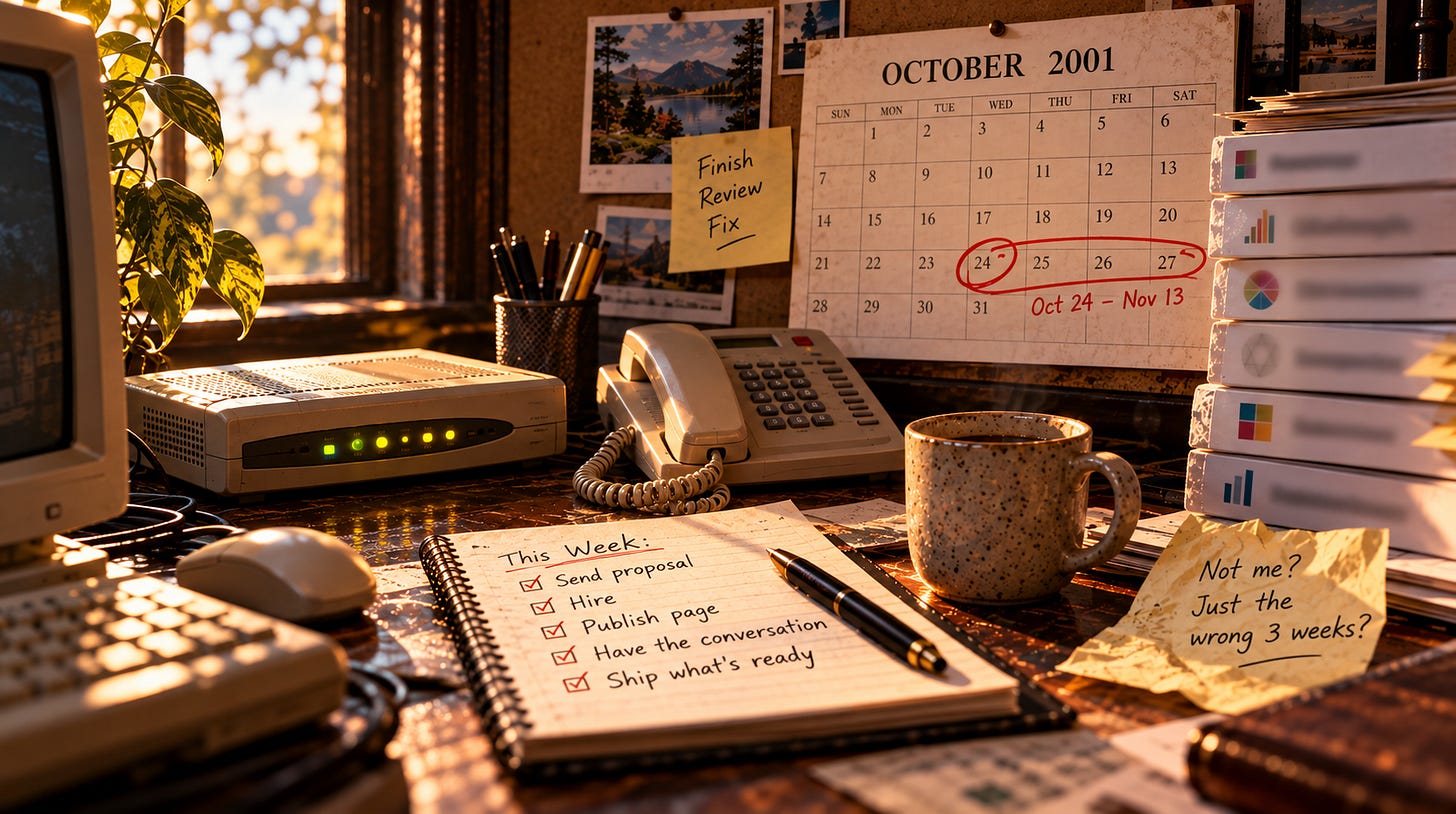 A sunlit 2001 office desk: beige modem, desk phone, an October 2001 wall calendar with the 24th circled and "Oct 24 - Nov 13" written beneath, a notebook headed "This Week" with ship what's ready ticked off, and a note reading "Not me? Just the wrong 3 weeks?" A sunlit 2001 office desk: beige modem, desk phone, an October 2001 wall calendar with the 24th circled and "Oct 24 - Nov 13" written beneath, a notebook headed "This Week" with ship what's ready ticked off, and a note reading "Not me? Just the wrong 3 weeks?"