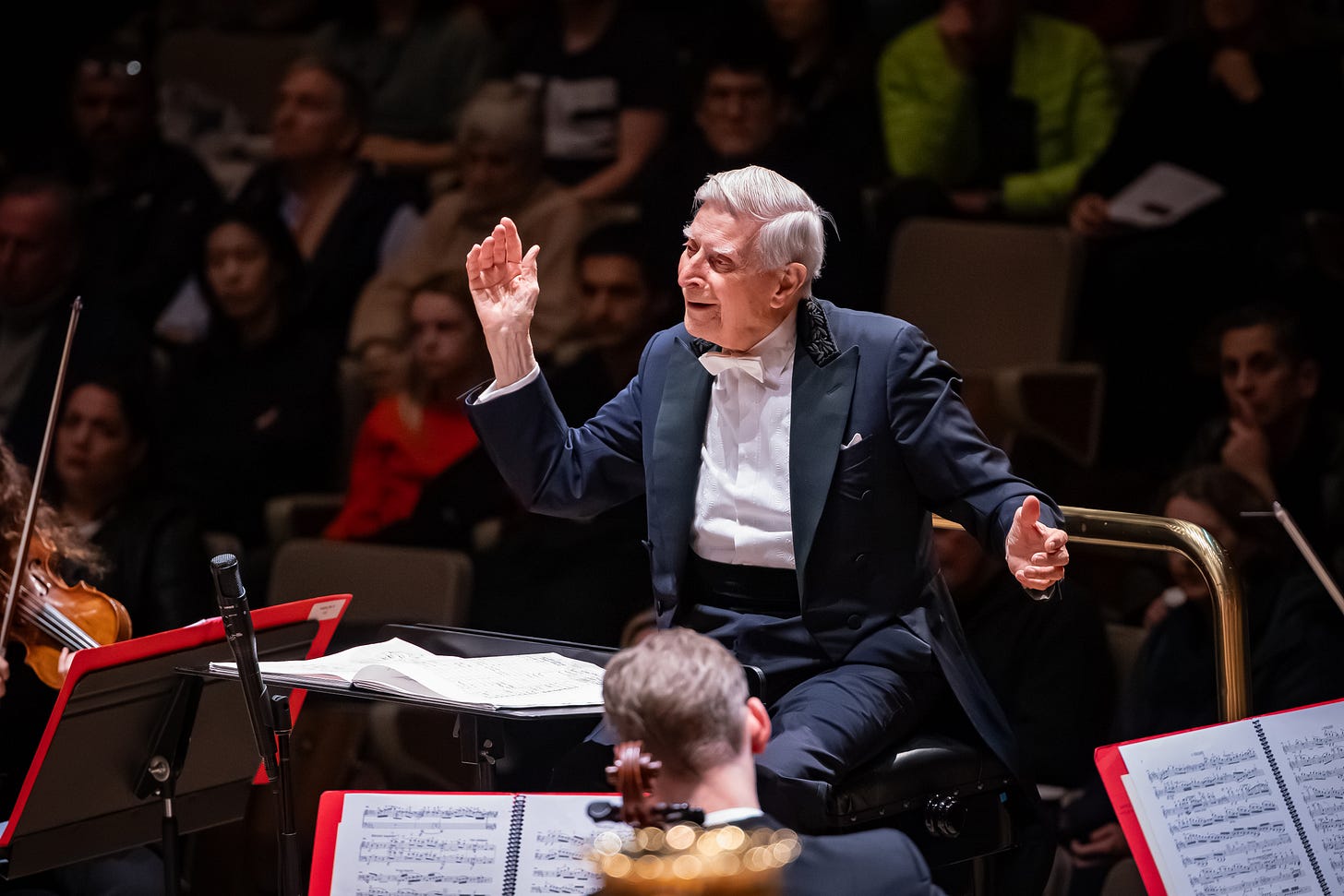 97-year old Herbert Blomstedt (seated) conducts, a smile on his face