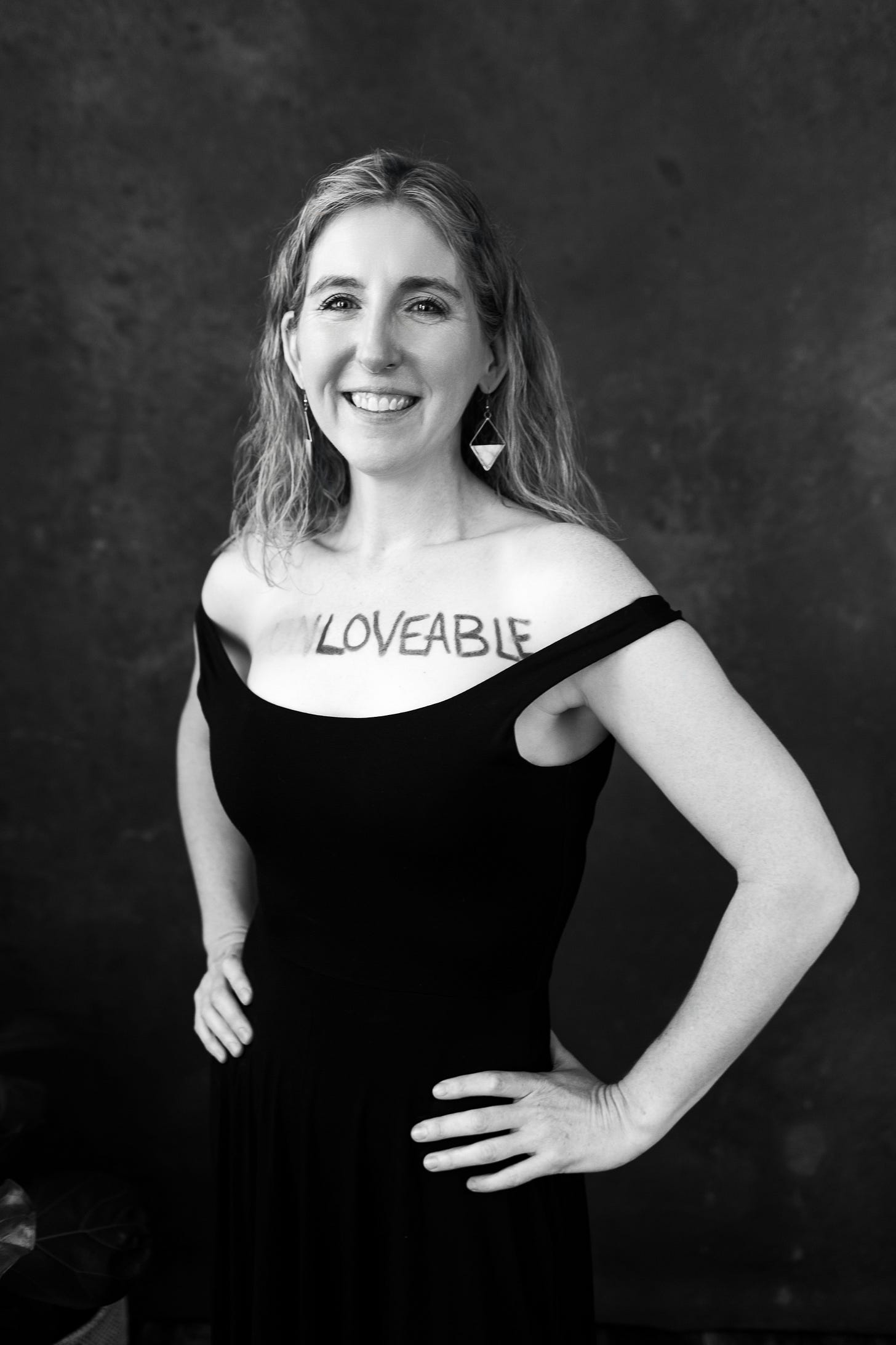 Black and white photo of a woman standing strong with loveable on her chest