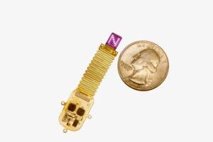 The thin, flexible, wireless device sits next to a quarter for scale. Device emits complex patterns of light (shown here as an "N") to transmit information directly to the brain.