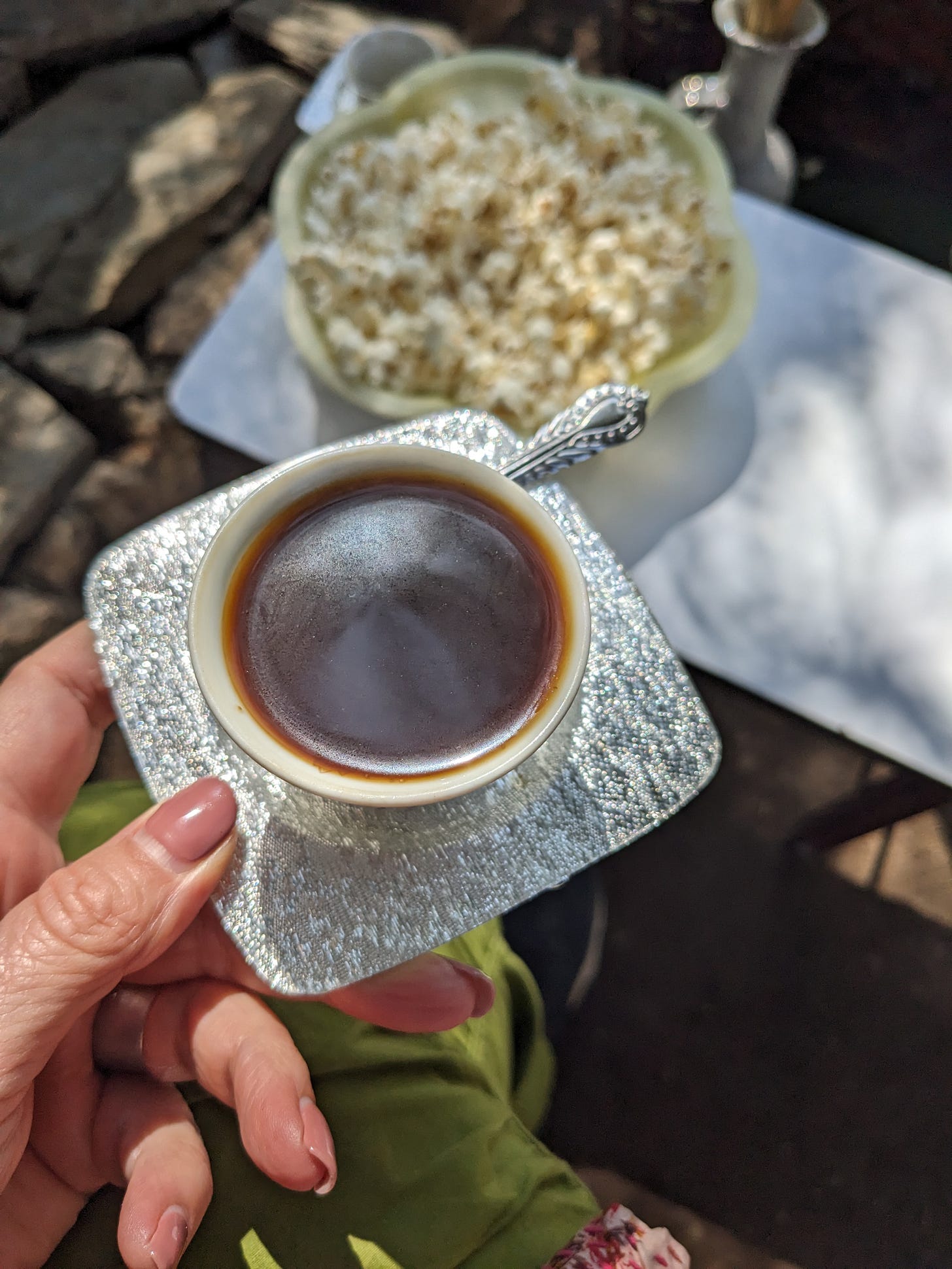 A white woman with pink nails is holding a small cup of coffee on a silver saucer. A white woman with pink nails is holding a small cup of coffee on a silver saucer.