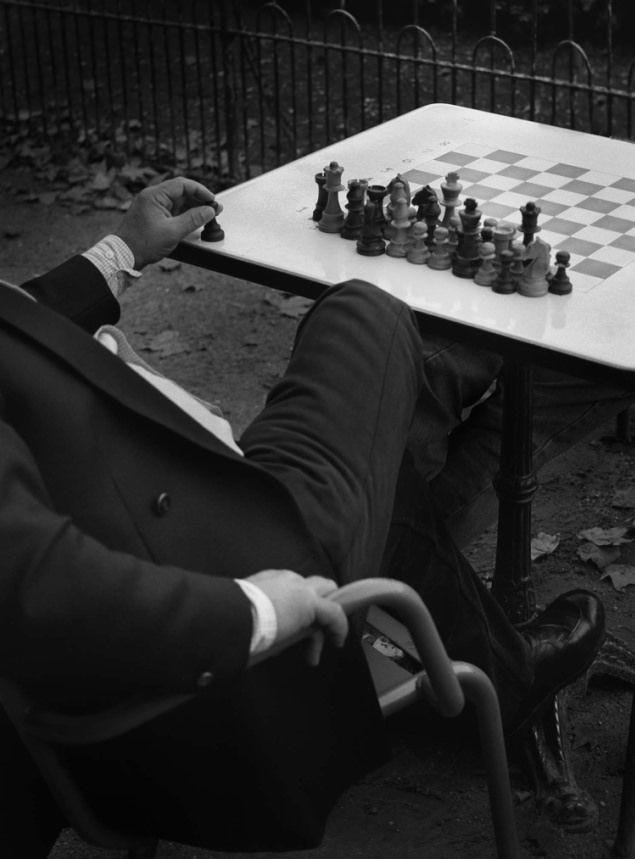 This may contain: a man sitting at a table playing chess
