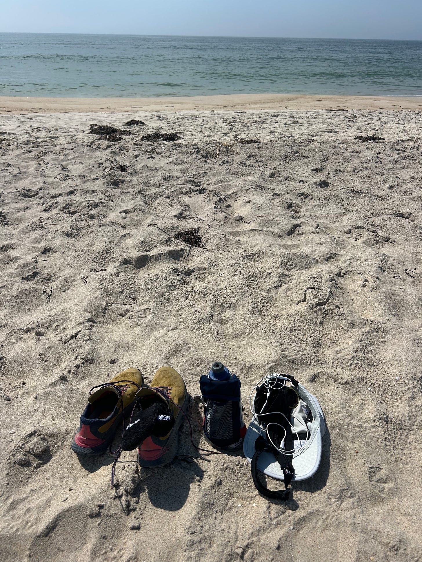 running shoes, a hat, and a water bottle, in front of a beach landscape