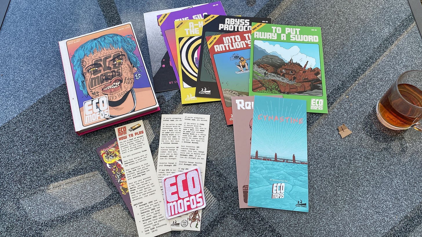 A table with the Eco Mofos main rules book next to the stack of Eco Mofos adventures