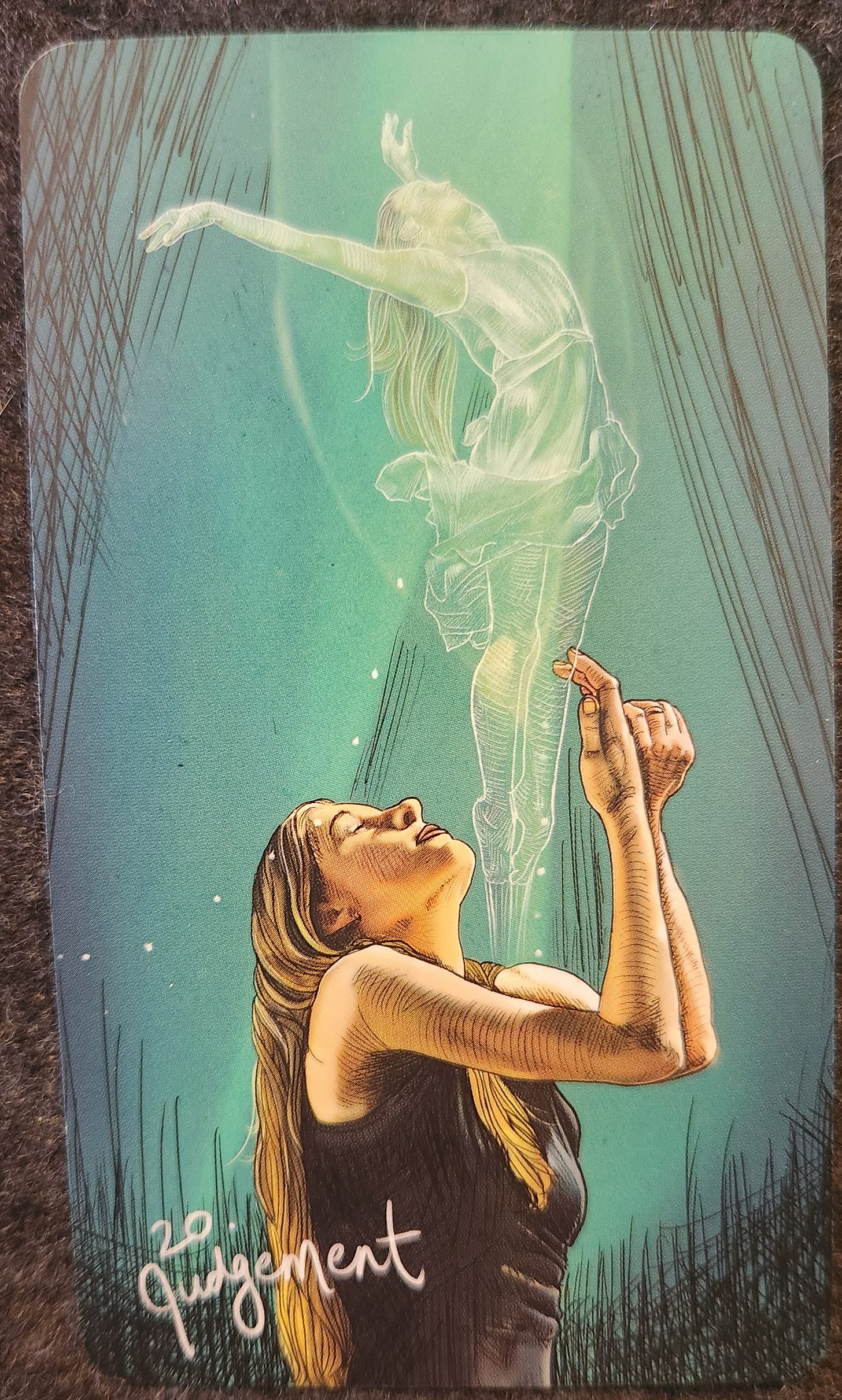 A tarot card labelled 20. Judgement. A woman is standing with her arms bent and raised up into the sky, her eyes closed, and her face uplifted. Above her, as though emerging from her body, is a silhouette of a person. Their arms outstretched, their body tall and proud. 
