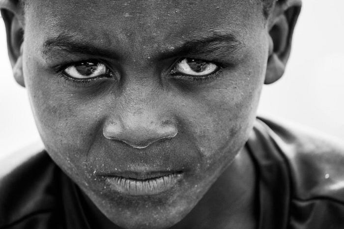 Young boy with dirty face staring grimly at camera