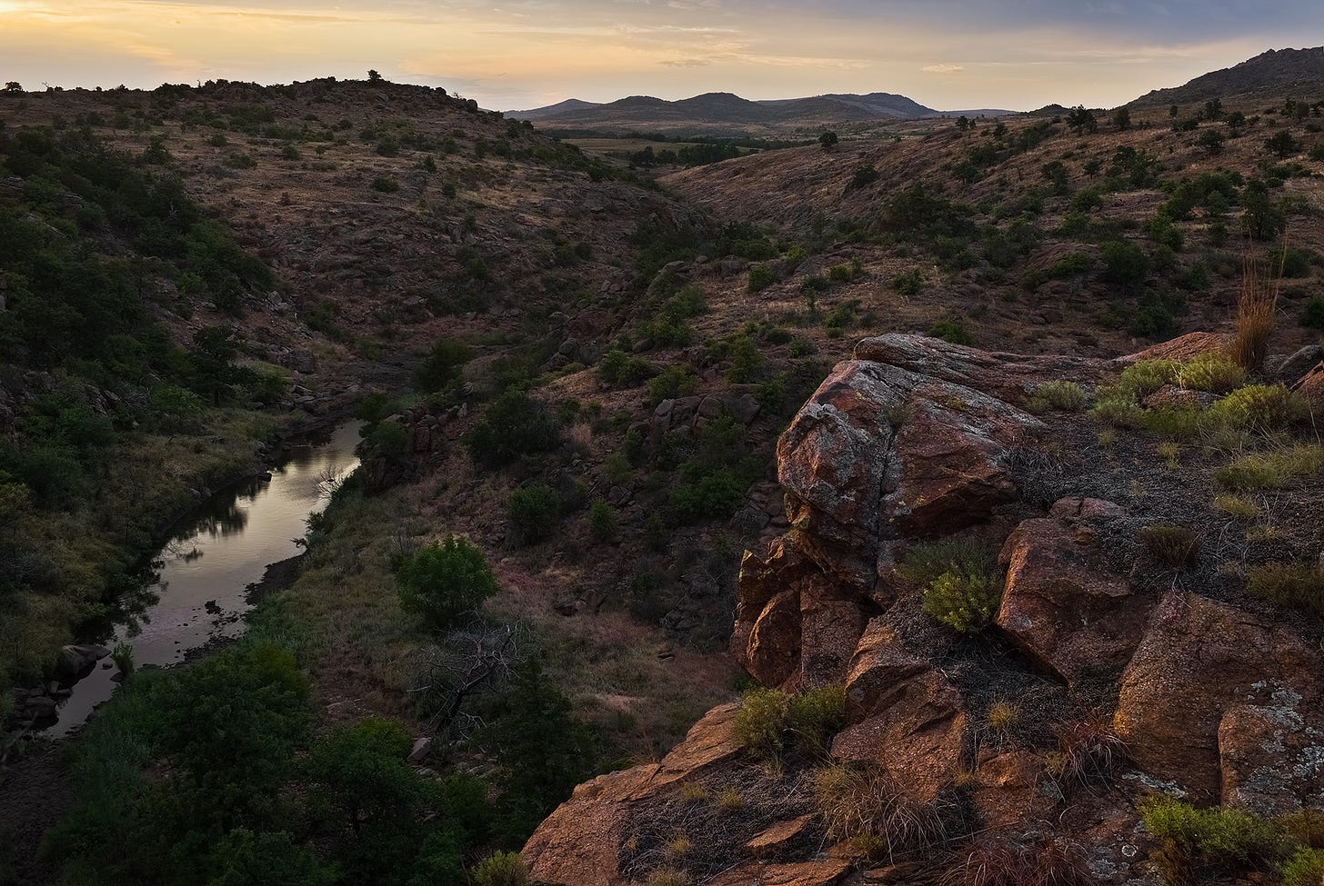Overlooking a gorge with a creek and mountains in the background.