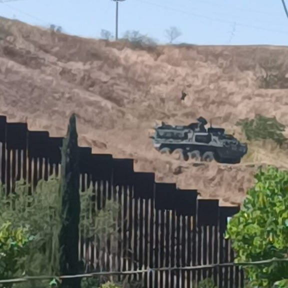 View of the border wall from Nogales, Mexico, as a US Army Stryker patrols the Arizona side in a show of force to deter illegal crossings.