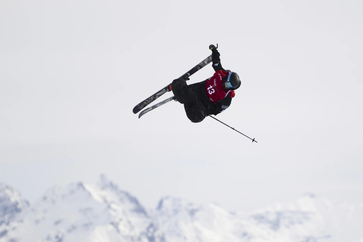 Jay Riccomini grabbing ski while flying through air.