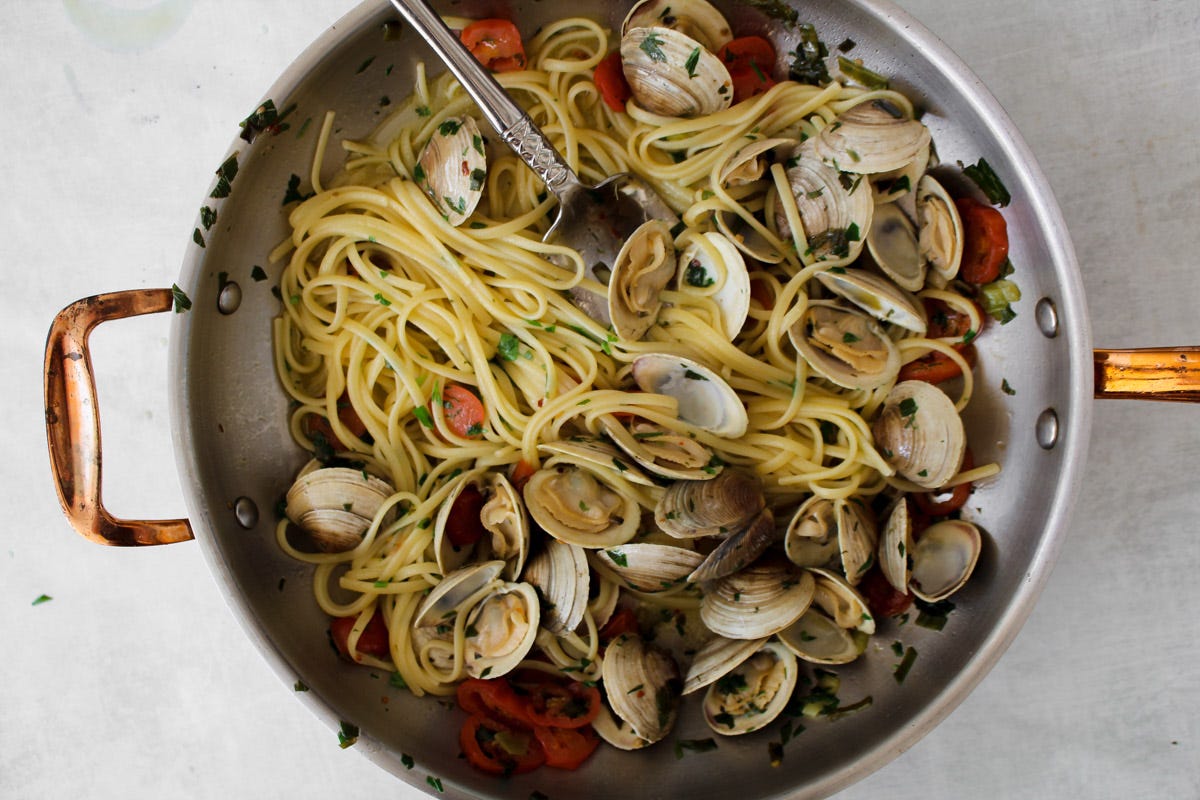 overhead image of linguine and clams in a large skillet. 