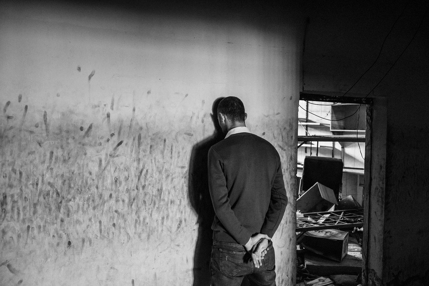 A blackandwhite photograph of a person with their head against the wall. A blackandwhite photograph of a person with their head against the wall.