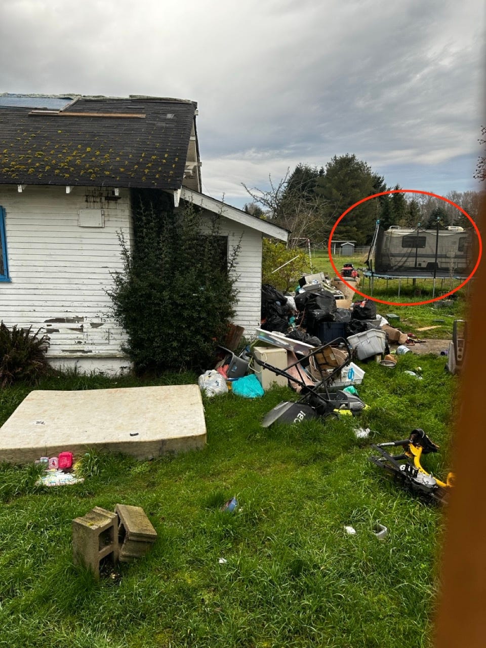 A house with a pile of trash in the grass

Description automatically generated