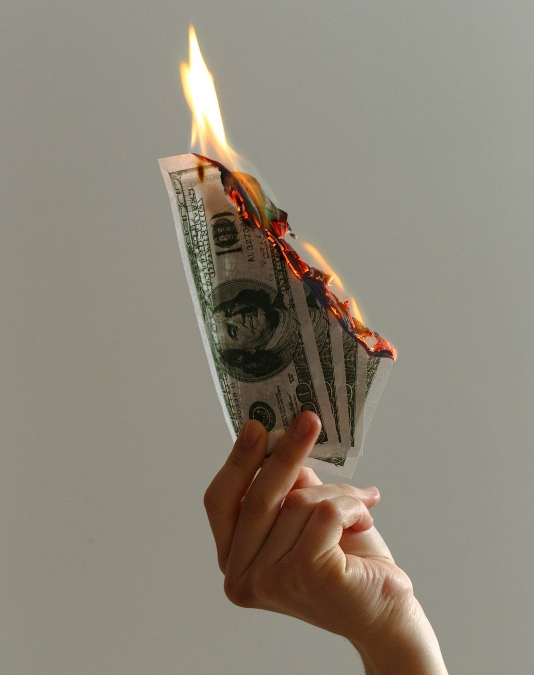 person holding lighted dollar bills