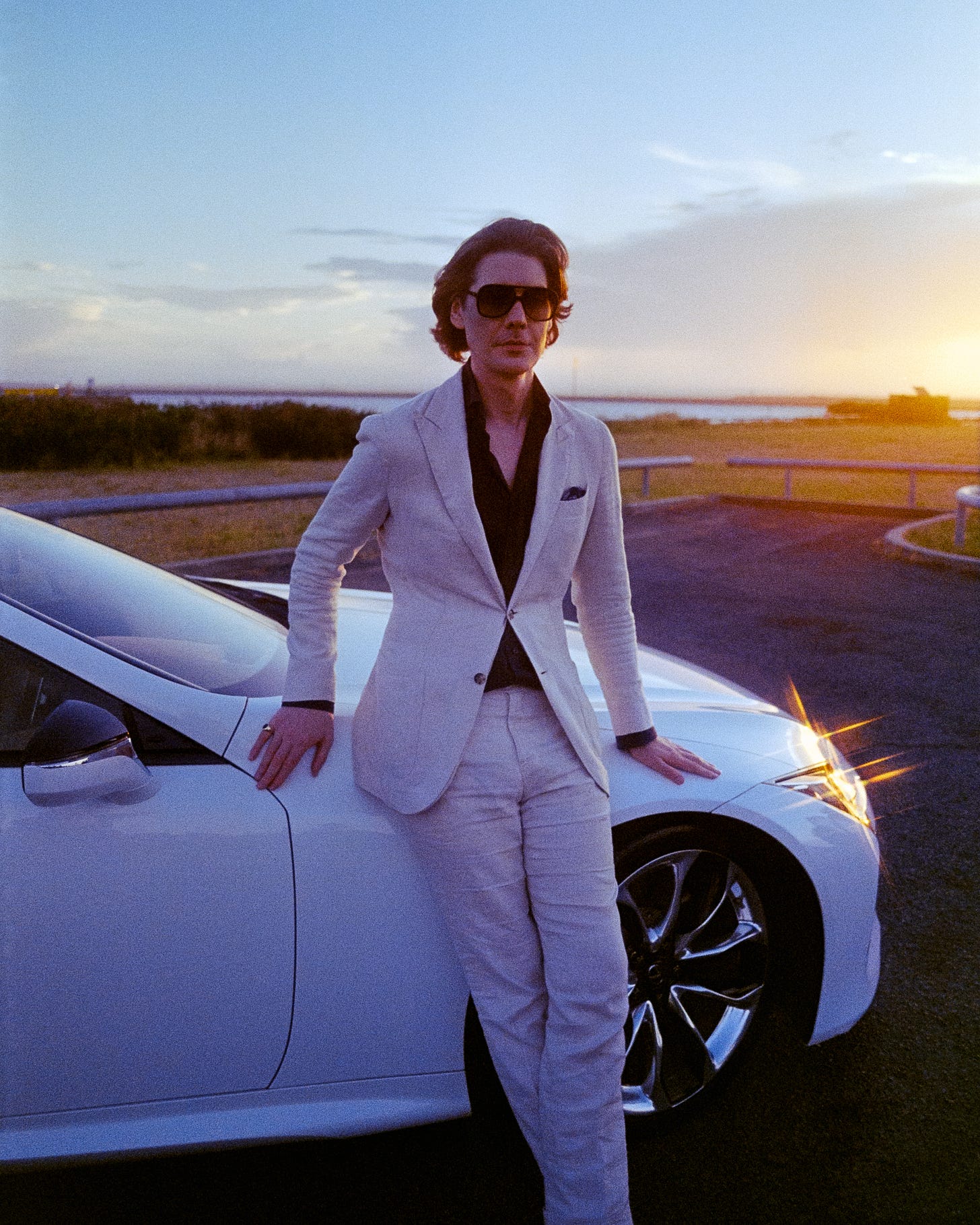 Clem leaning against his car with aviator sunglasses on, looking very chill as the sunset reflects off the headlights. Clem leaning against his car with aviator sunglasses on, looking very chill as the sunset reflects off the headlights.