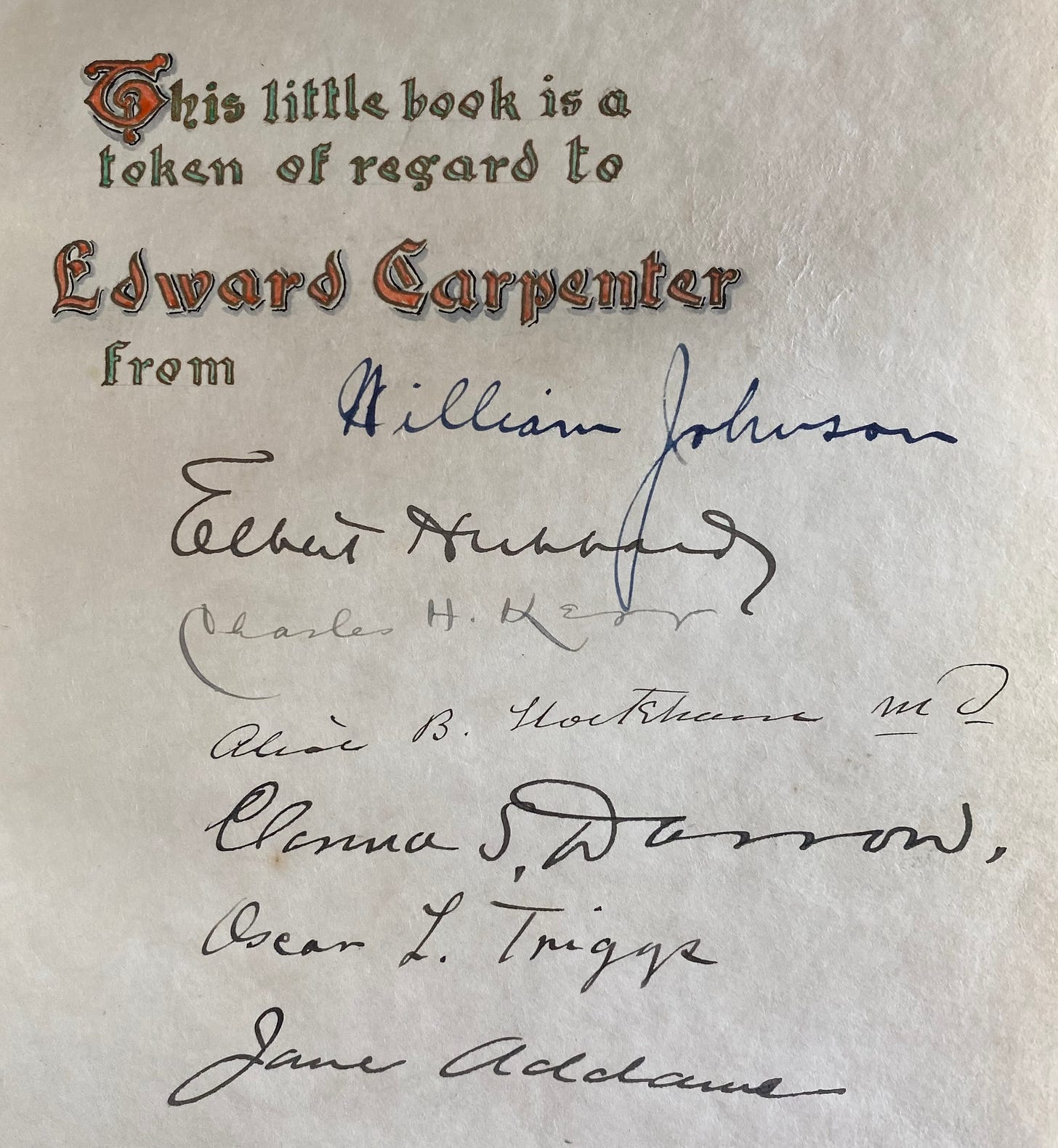 Close-up photograph of the illuminated dedication page from the 1904 Roycroft edition of Song of Myself. At the top, ornate Gothic lettering in red and green reads, “This little book is a token of regard to Edward Carpenter.” Beneath it appear handwritten signatures in dark ink, including William Johnson, Elbert Hubbard, Charles H. Kerr, Alice B. Stockham, Clarence S. Darrow, Oscar L. Triggs, and Jane Addams.