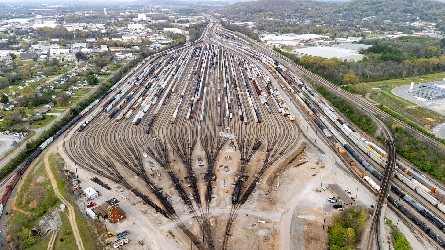 Aerial view of a large rail classification yard with rows of freight cars fanning out across tracks. 