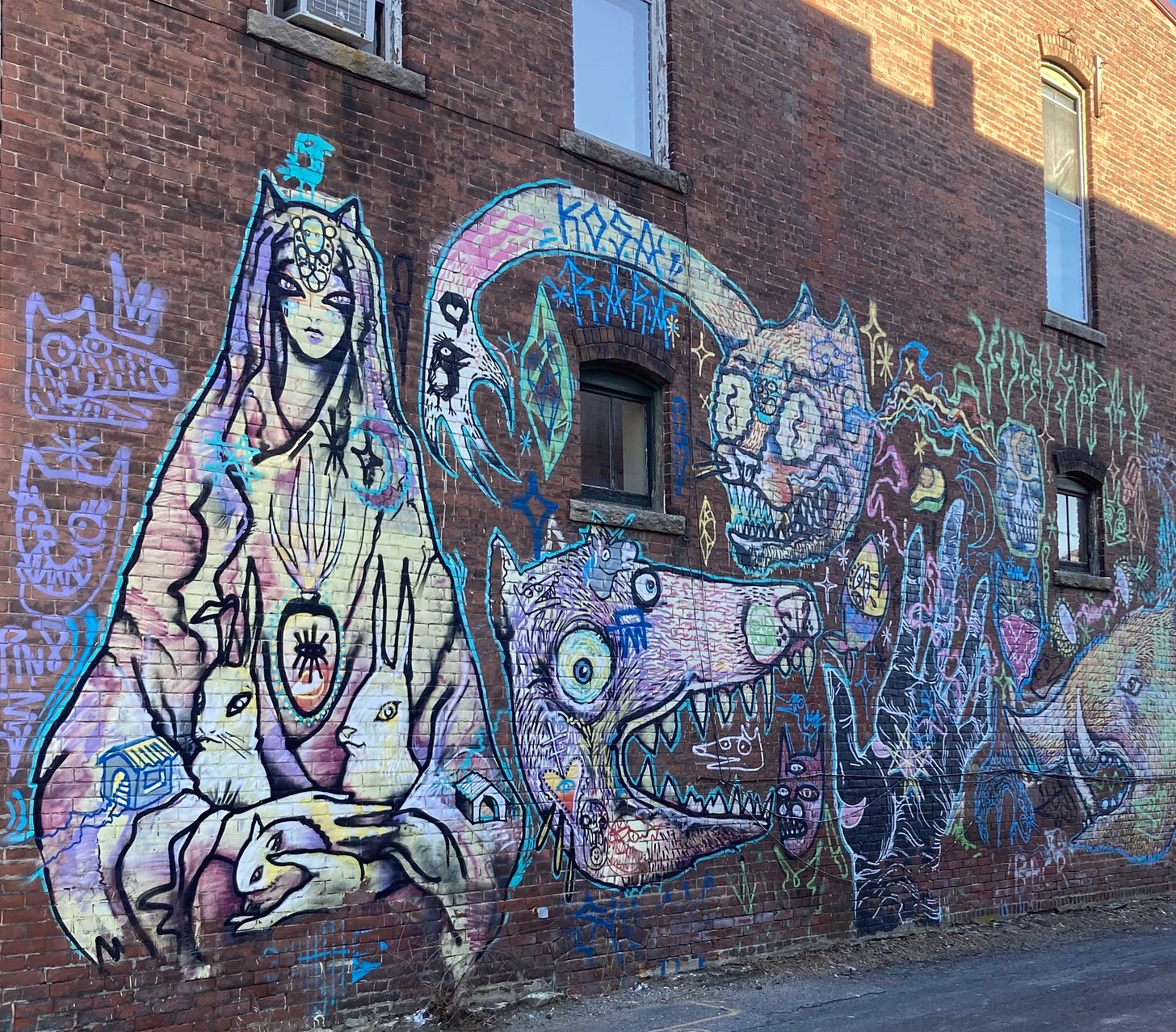 Art on brick. A seated figure holds two rabbits near a slightly monstrous-looking dog(?) and a cat(?)
