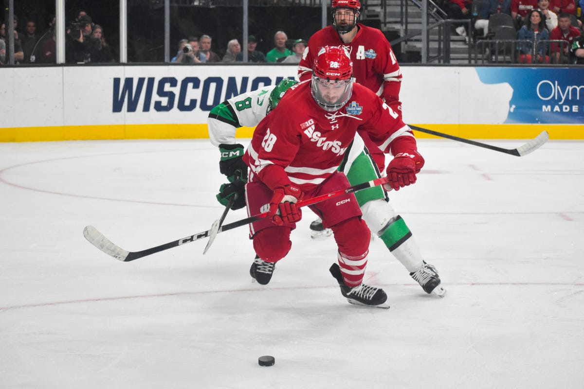 Badger hockey defenseman Aiden Dubinsky stares down a puck on the right faceoff circle