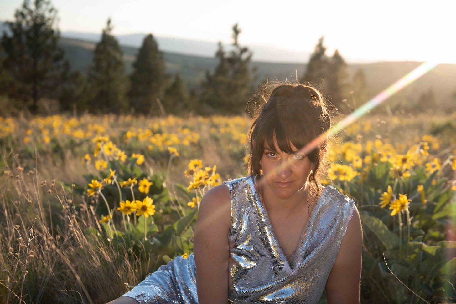 woman in silver dress in field of yellow flowers