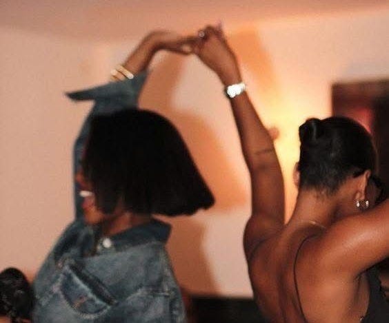 This may contain: two women are dancing together in the living room, one is wearing a jean jacket