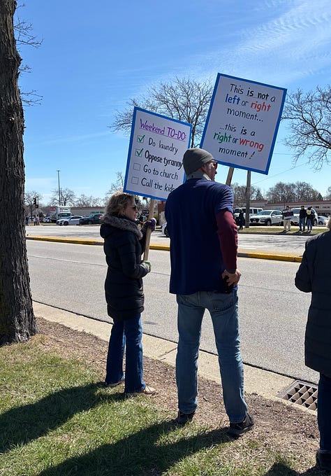 Protesters and dogs with signs at an outdoor rally