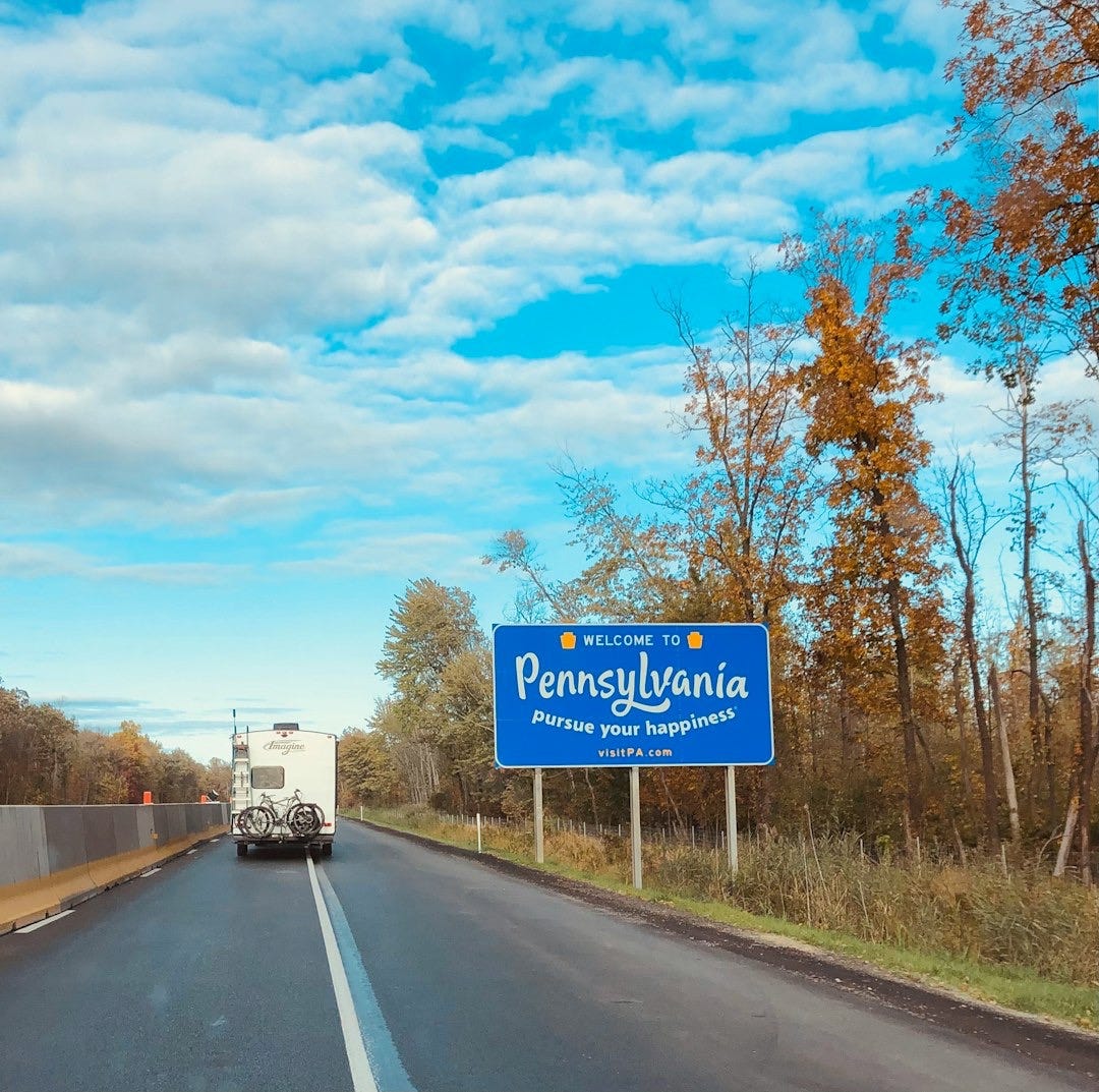 blue and white road sign near trees during daytime