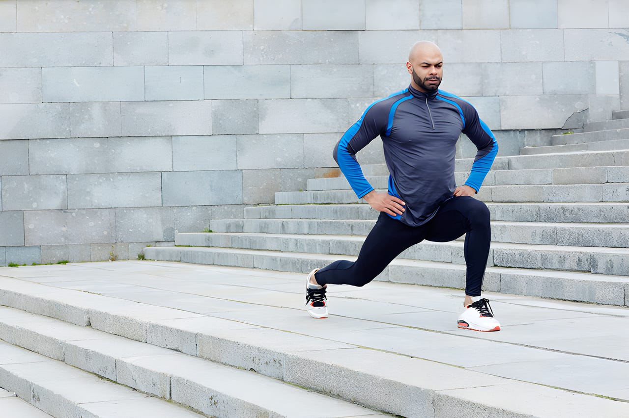 Man wearing athletic gear performing a lunge on outdoor steps.
