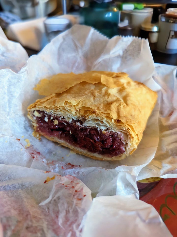 Left: A cherry strudel in parchment paper; right: a broken horseshoe cookie with a bowl of popcorn in the background.