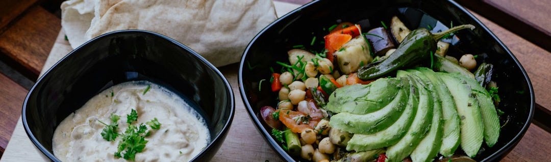 Two bowls of food featuring fresh vegetables and other vegan treats Two bowls of food featuring fresh vegetables and other vegan treats