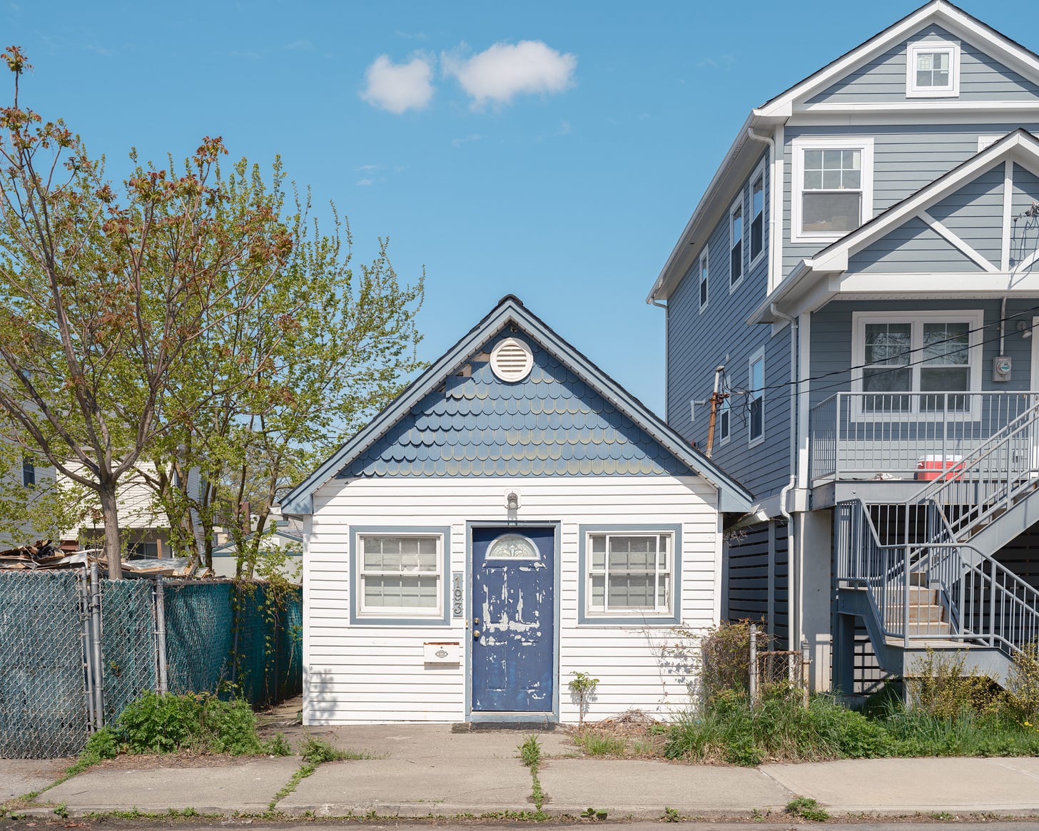 blue-and-white-wood-shingled-bungalow-under-lone-cloud