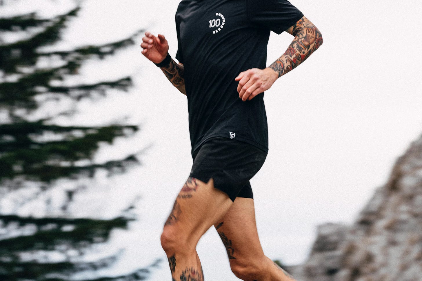 the author wearing a runhundred shirt and trail running in the mountains