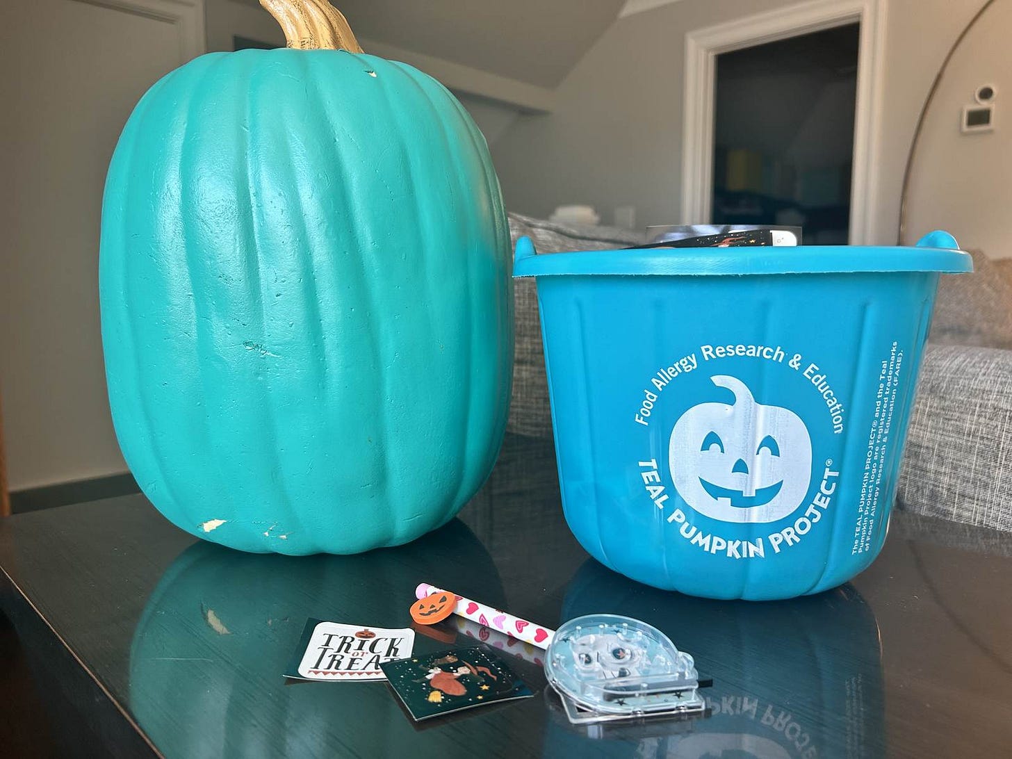 A teal pumpkin on a front porch filled with non-candy items like stickers and pencils with Halloween erasers. A teal pumpkin on a front porch filled with non-candy items like stickers and pencils with Halloween erasers.