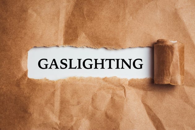 the word Gaslighting appearing behind torn brown paper. the word Gaslighting appearing behind torn brown paper.