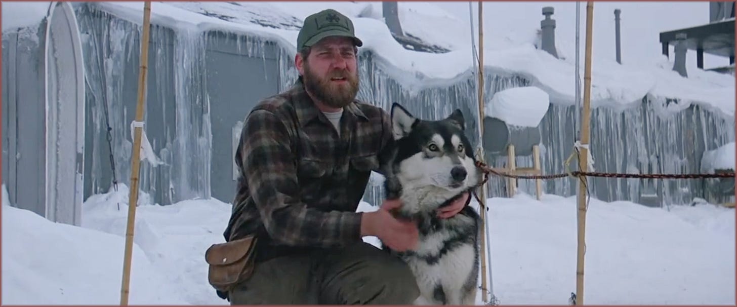 Film frame from The Thing (1982): Clark (Richard Masur) crouching in the snow outside Outpost 31, arms around Jed the wolf-malamute hybrid